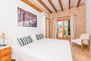 a bedroom with a bed and a chair and a window at Sa Fusteria in Sóller