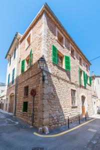 a stone building with green shuttered windows and a street at Sa Fusteria in Sóller
