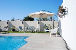 a patio with an umbrella and chairs and a pool at Beautiful Traditional House in Chipiona