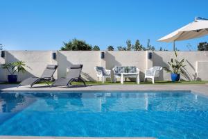 a pool with chairs and a table and an umbrella at Beautiful Traditional House in Chipiona
