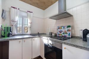 a kitchen with white cabinets and a sink and a window at Beautiful Traditional House in Chipiona
