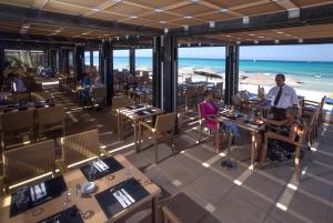 ein Restaurant mit Leuten, die am Strand an Tischen sitzen in der Unterkunft Sentido Djerba Beach in Midoun