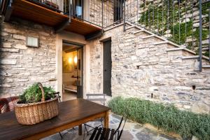 a patio with a wooden table and a stone wall at Appartamento Panoramico Como in Blevio
