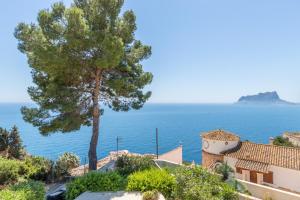 a tree and a house with the ocean in the background at Casa Viviana in Moraira