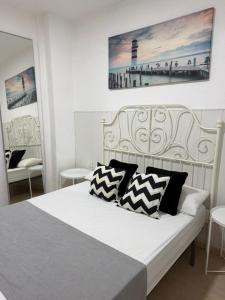 a bedroom with a white bed with black and white pillows at apartamento el camarote in Fasnia