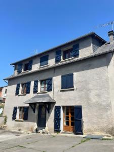 a large white building with blue doors and windows at Chaleureuse Maison de Montagne in Garin
