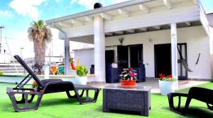 a patio with chairs and a table on a green lawn at Capital Bed Porto Cesareo in Porto Cesareo