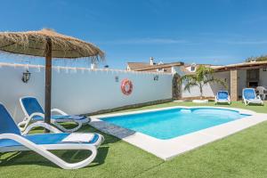 a swimming pool with chairs and an umbrella at Casa Capricho in Vejer de la Frontera