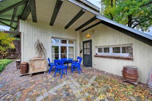 a patio with a blue table and chairs in front of a house at Das Künstlerhaus - dein Sommerhaus in Köckern