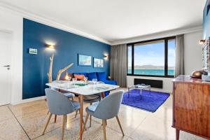 a dining room with blue walls and a table and chairs at Exception Maison pieds dans l'eau in Fréjus