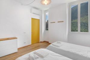 a white bedroom with two beds and a yellow door at Workation Castle - Casa Galbiga in Carlazzo