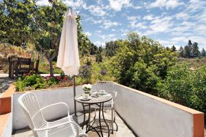 a patio with a table and an umbrella and chairs at Casa Rodri in Puntagorda