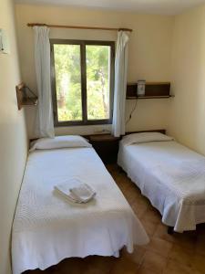 two beds in a room with a window at Villetta Son Bou in Son Bou