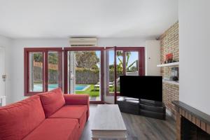 a living room with a red couch and a tv at Casa-piscina privada en Vallpineda in Sant Pere de Ribes