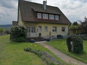 a yellow house with a porch and a yard at Ferienwohnung Kirsch-Kern in Mössingen