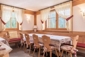 a dining room with a table and chairs and windows at Chalet Crepes De Sela in Canazei