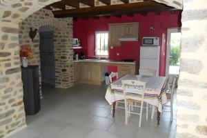 a kitchen with a table and a red wall at Gîte De La Haie Bourgère in Moulay