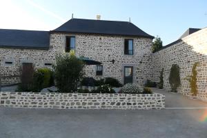 a stone house with a stone wall and a building at Gîte De La Haie Bourgère in Moulay
