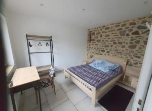 a small bedroom with a bed and a brick wall at Gîte De La Haie Bourgère in Moulay