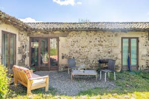 a stone house with a patio with chairs and a piano at Gîtes Bourdeverre in Sanxay