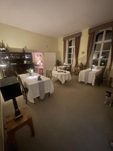 a dining room with two tables with white table cloth at Gutsherren Räume in Groß Upahl