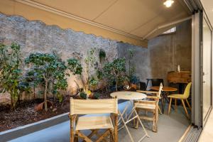 a room with tables and chairs and a wall with plants at The Apex Boutique Studio in Athens