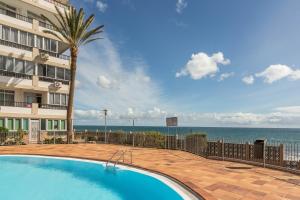 a swimming pool in front of a building with the ocean at Apartamento Soraya in San Bartolomé