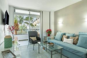 a living room with a blue couch and a glass table at Apartamento Soraya in San Bartolomé