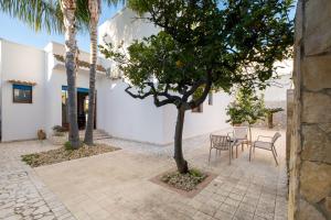 a courtyard with a table and chairs and palm trees at By The Sea – Le Chele in Torre Lapillo
