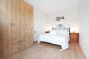 a bedroom with a white bed and a wooden cabinet at Finca Lucrecia in Fasnia +25 photos