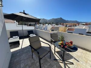 a balcony with a table and chairs and an umbrella at Chalet Mar Y Montaña in Los Silos