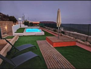 a backyard with a swimming pool and an umbrella at Finca Lucrecia in Fasnia
