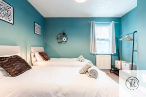 two beds in a room with blue walls at Shamrock House in Ipswich