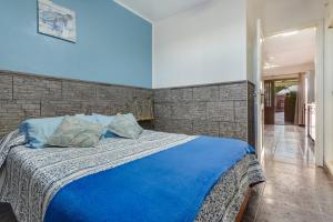 a bedroom with a blue bed with a brick wall at Casa Lita in Antigua +16 photos