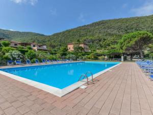 a swimming pool with chairs and mountains in the background at Altaluna Apartment with Pool in Nisporto