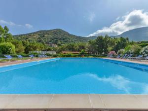 a swimming pool with chairs and mountains in the background at Altaluna Apartment with Pool in Nisporto