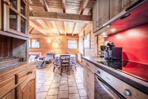 a kitchen with a table and a red wall at Chalet 6p Classique - Amarock in Verchaix +12 photos