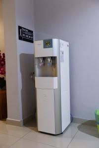 a small white refrigerator next to a wall at Brezza Hotel Lumut in Lumut