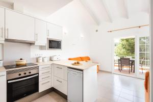 a kitchen with white cabinets and a stove top oven at Apartamento Dos Geckos in Son Parc
