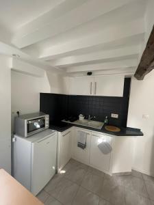 a small kitchen with white cabinets and a sink at Logement Cosy centre Joigny C4 in Joigny +6 photos