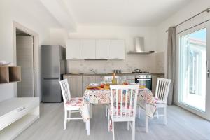 a kitchen with a table with chairs and a kitchen with white cabinets at Venere cala gonone vista mare in Cala Gonone