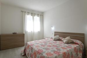 a bedroom with a bed with a floral bedspread and a window at Venere cala gonone vista mare in Cala Gonone