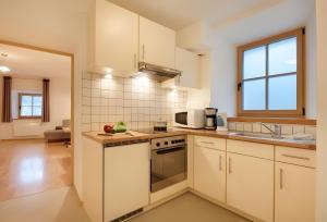 a kitchen with white cabinets and a stove top oven at Rafaser - Apartment Albina in Feldthurns