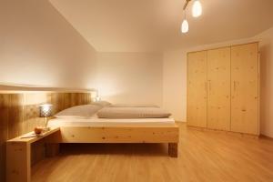 a bedroom with a wooden bed and a cabinet at Rafaser - Apartment Albina in Feldthurns
