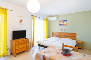 a bedroom with two beds and a tv and a table at Les Mimosas - Appartement 10 in Cazaubon