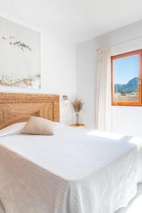 a white bedroom with a large bed with a window at Miramar in Artá