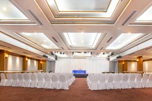 a room with rows of white chairs in a hall at Phrae Nakara Hotel in Phrae