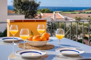 a table with a bowl of oranges and glasses of wine at Petit Paradis Apartment in Son Bou