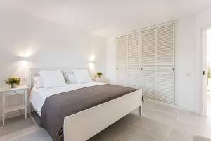a white bedroom with a large bed and a window at Petit Paradis Apartment in Son Bou