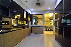 Una cocina con gabinetes de madera y un comedor. en Plumeria Luxury Service Villa, en George Town
